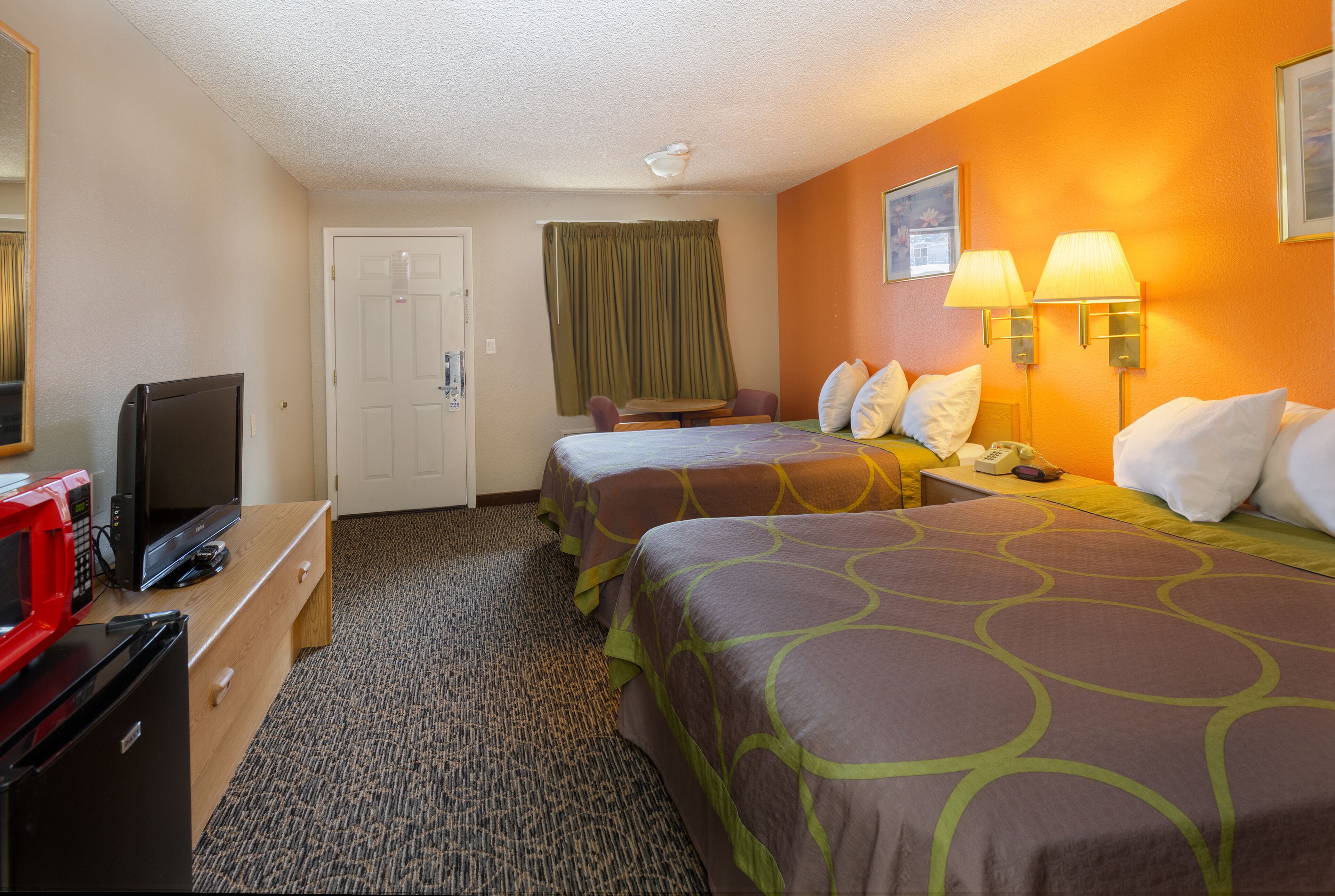 Habitación de hotel con dos camas, televisión, escritorio con teléfono y microondas.