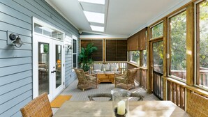 A covered porch with a wooden table, wicker chairs, and a sofa. - High-End Beach Home, Walking Distance to Beach & Close To Town - On The Half Shell! (Folly Beach)