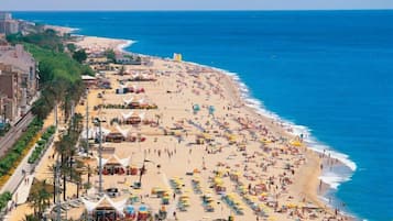 Una platja plena de gent i nombrosos para-sols.