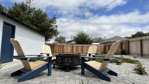 Een terras met Adirondack-stoelen en een vuurkuil.