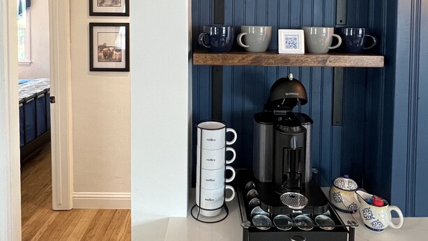 Een keuken met een koffiebar, inclusief planken met mokken, een koffiezetapparaat en een koffiemolen.