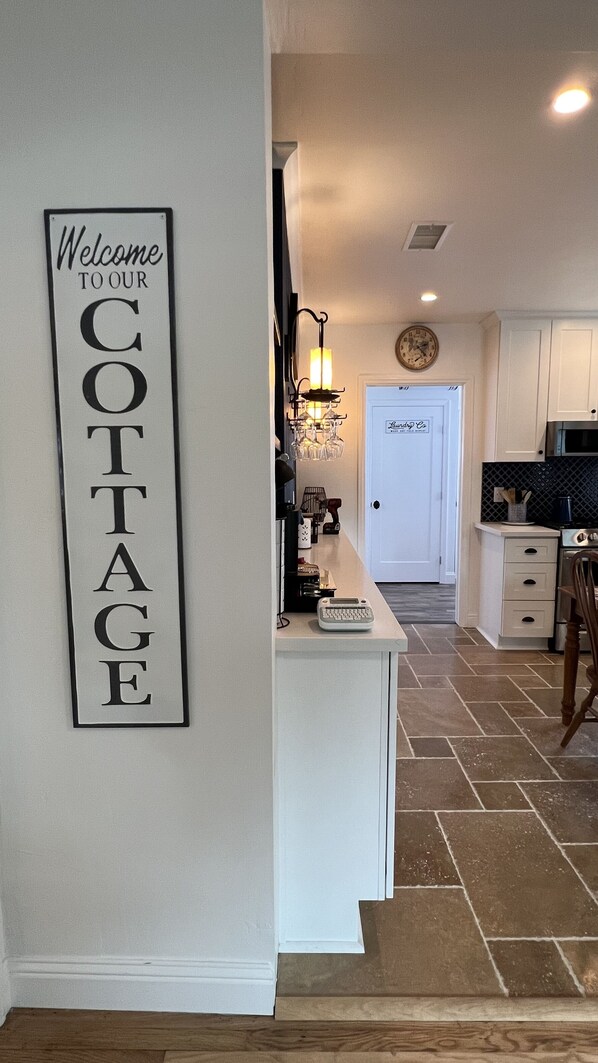 A kitchen with a welcome sign, a chandelier, and a door labeled 'Living Room'.
