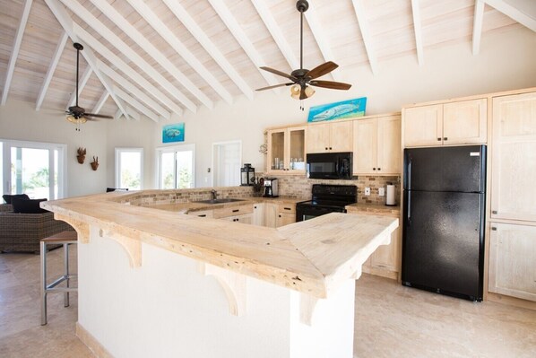 A spacious kitchen with a large island, wooden cabinets, and a black refrigerator.