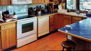 Una cocina con armarios de madera, un microondas, una estufa y un lavaplatos.