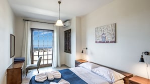 Ein Hotelzimmer mit Bett, Schreibtisch, Stuhl, einem Fenster mit Blick und einem Bild an der Wand.