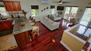 A spacious living area with a kitchen, dining area, and a balcony. - Sunset and Ocean views at Sandy Feet Retreat with private infinity pool. (Sandy Bay)
