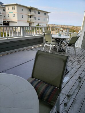 Eine Terrasse mit Sitzgelegenheiten, einem Tisch und Blick auf ein gegenüberliegendes Gebäude.
