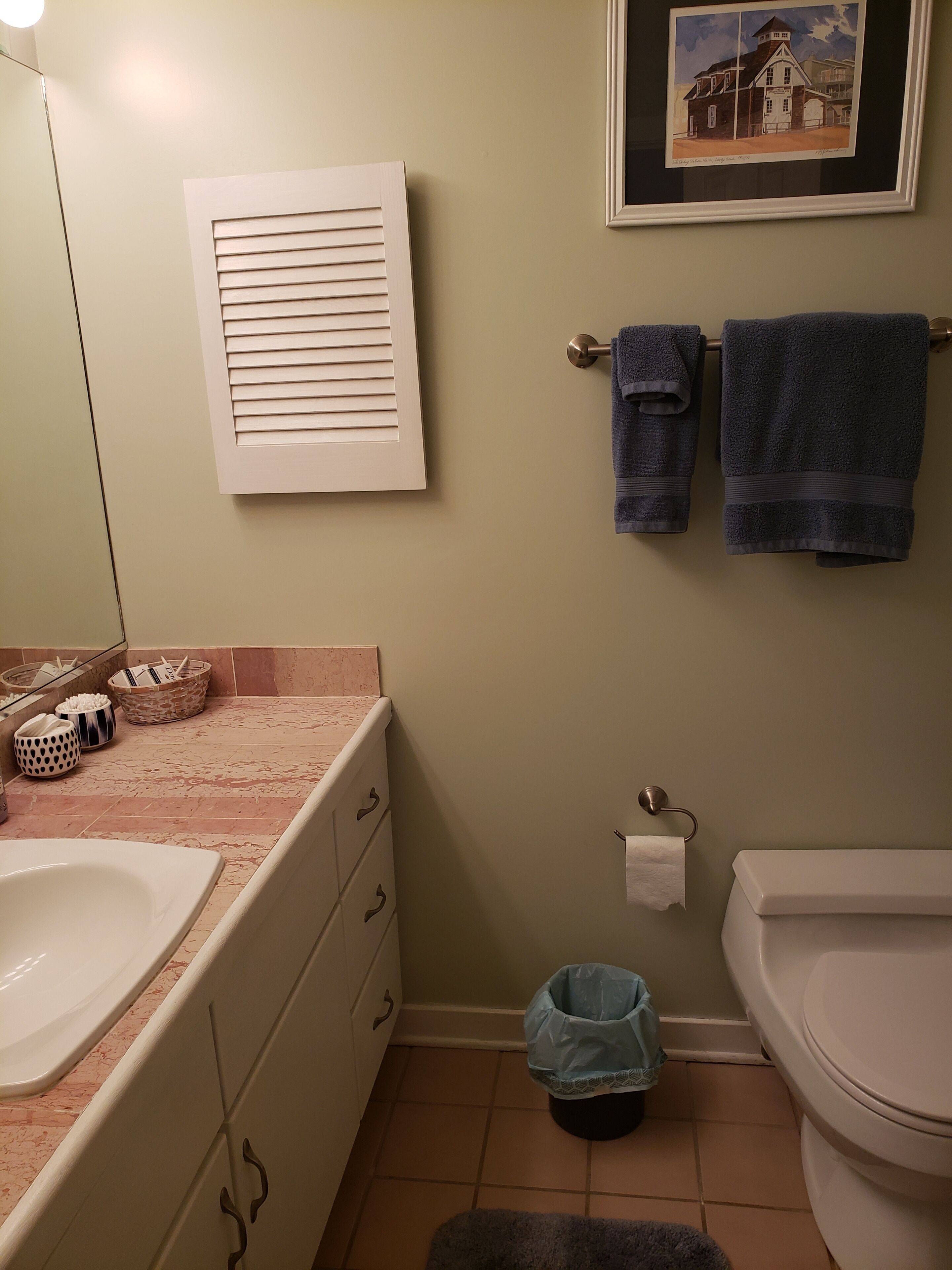A bathroom with a sink, toilet, and framed artwork on the wall.