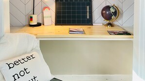 Un espace de travail comprenant un bureau en bois, des étagères, un globe terrestre, une horloge et un calendrier.