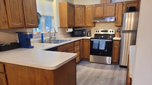 A kitchen with wooden cabinets, a stainless steel refrigerator, a built-in oven, and a microwave. - Cozy centrally located two-bedroom home. Pet friendly!  (Fairbanks)