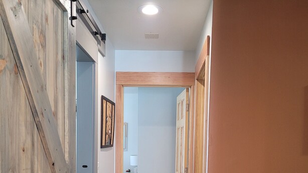 A hallway with a wooden door on the left, a light switch on the wall, and a power outlet on the right. - Cozy centrally located two-bedroom home. Pet friendly!  (Fairbanks)
