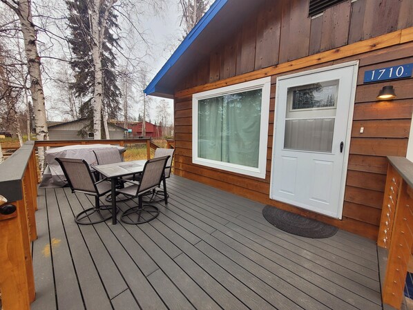 A wooden deck with a table and chairs, a covered outdoor seating area, and a house number 1710.