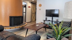 A living room with a fireplace, a television, and a sofa. - Cozy centrally located two-bedroom home. Pet friendly!  (Fairbanks)