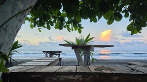 A wooden pier with a bench and a table extending onto a beach.