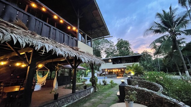 A two-story building with a thatched roof patio and string lights.