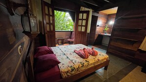A wooden room with a bed, a small table, and a window with a view of greenery.