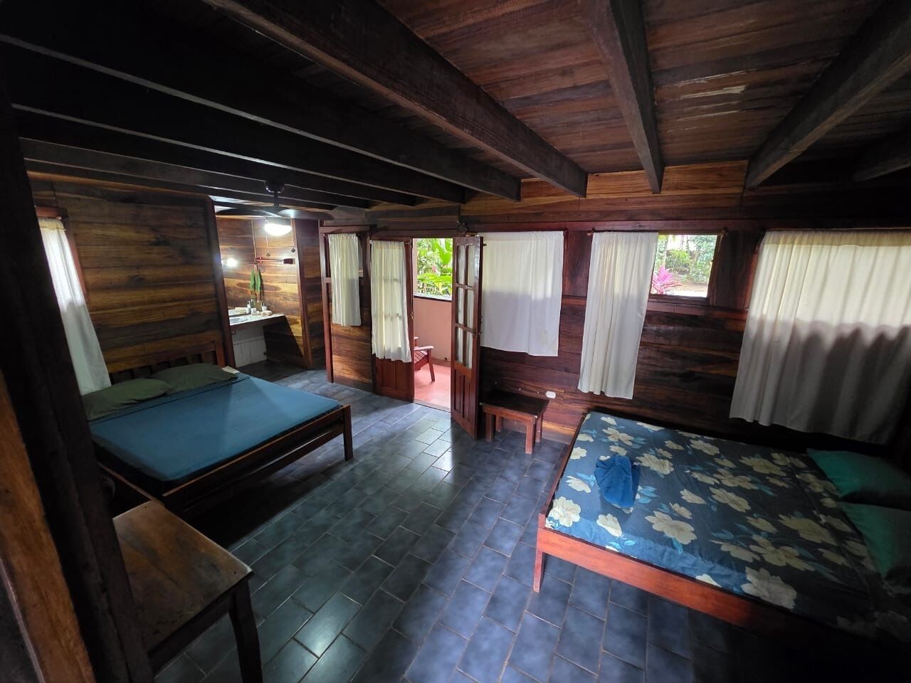 A wooden cabin with two beds, a small table, and a bench.