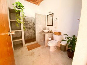 A compact bathroom with a toilet, sink, and a small shelf.