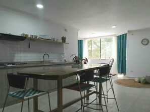 A kitchen with a central island, bar stools, and a dining table.