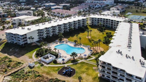 Un hôtel à plusieurs étages doté d’une piscine centrale, entourée d’espaces de détente et de palmiers.