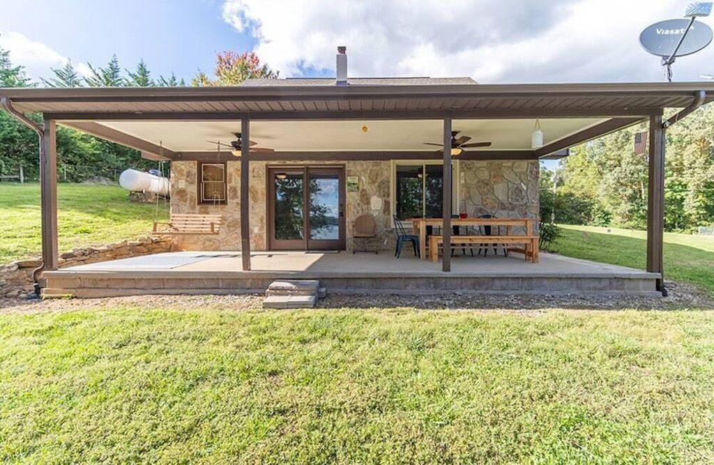 Une terrasse couverte avec un revêtement extérieur en pierre, un banc en bois et une antenne parabolique.