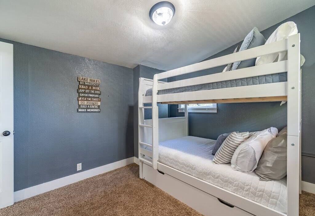 A bunk bed room with a grey wall and a ceiling light fixture.