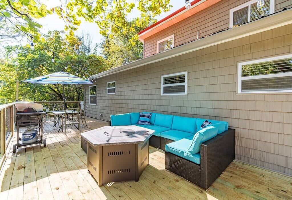 An outdoor deck with a blue sofa, a grill, and a table.