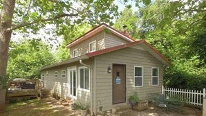 A single-story house with a front porch, a small attached garage, and a white picket fence.