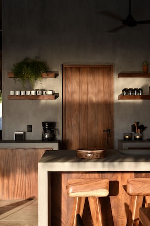 A modern kitchen with wooden cabinets, a coffee machine, and a built-in island with bar stools. - Casa Costamor - Beach front villa w/ 4 suites (Municipio de la Union, Montes de Oca)