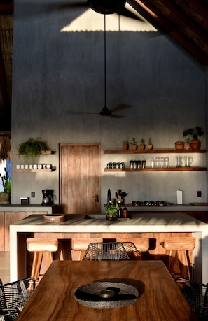 A modern kitchen with wooden countertops, a central island, and built-in shelves with plants and kitchenware. - Casa Costamor - Beach front villa w/ 4 suites (Municipio de la Union, Montes de Oca)