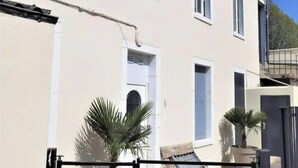 En toetages bygning med en beige facade, flere vinduer og en port.