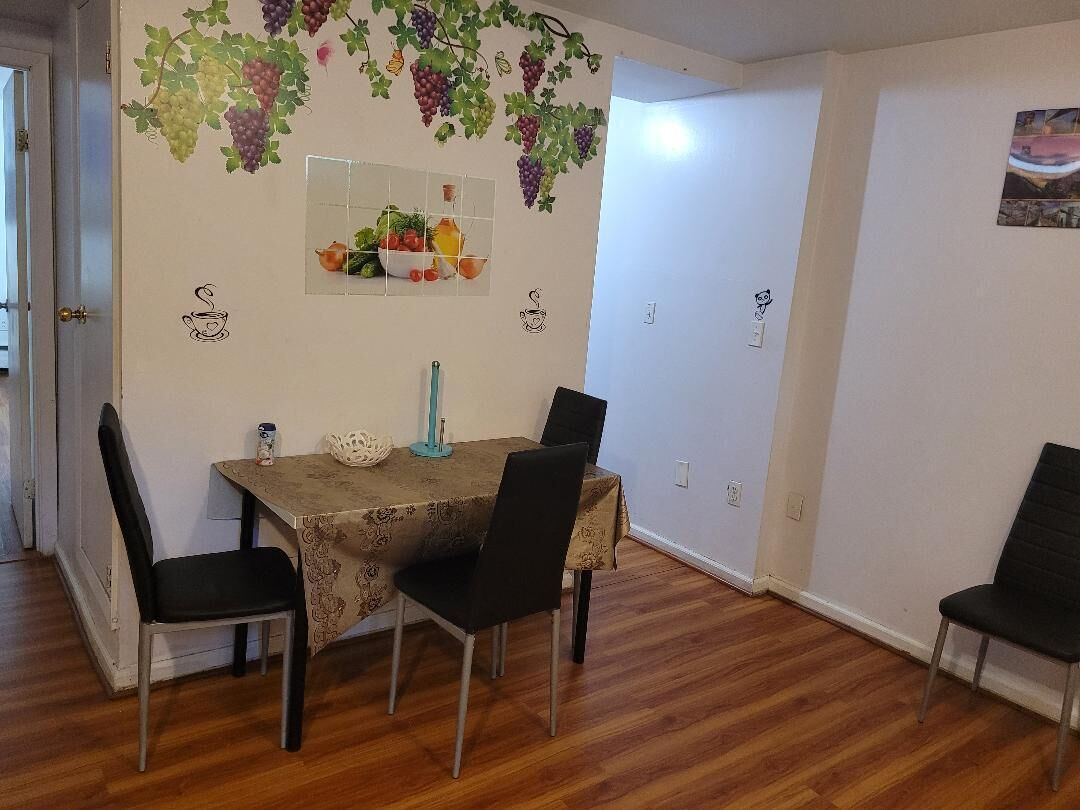Un coin repas avec une table dressée pour quatre personnes, entourée de chaises.