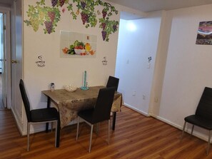 A dining area with a table set for four, surrounded by chairs.