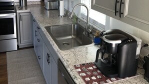 Een moderne keuken met roestvrijstalen apparatuur, een granieten aanrechtblad en witte kasten.