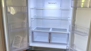 Een koelkast met meerdere transparante planken en een bedieningspaneel met de tekst 'Twin Cooling Plus'.