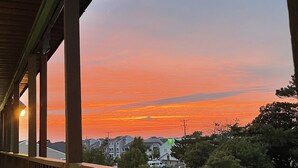 Un balcón con vista a un atardecer sobre una zona residencial.