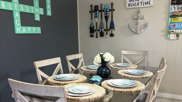 Un comedor con una mesa de madera dispuesta para seis personas, rodeado de sillas.