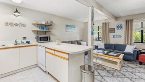 Un espacio habitable compacto con kitchenette, un sofá, una mesa de centro y vistas a zonas verdes.