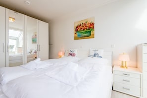 Ein Hotelzimmer mit einem großen Bett, einem Nachttisch mit Lampe, einem Schminktisch und einem Blumenbild an der Wand.