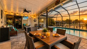 An outdoor dining area with a pool view, wicker furniture, and a breakfast setting.
