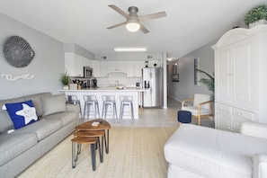 A modern kitchen with white cabinets, a central island, and bar stools.