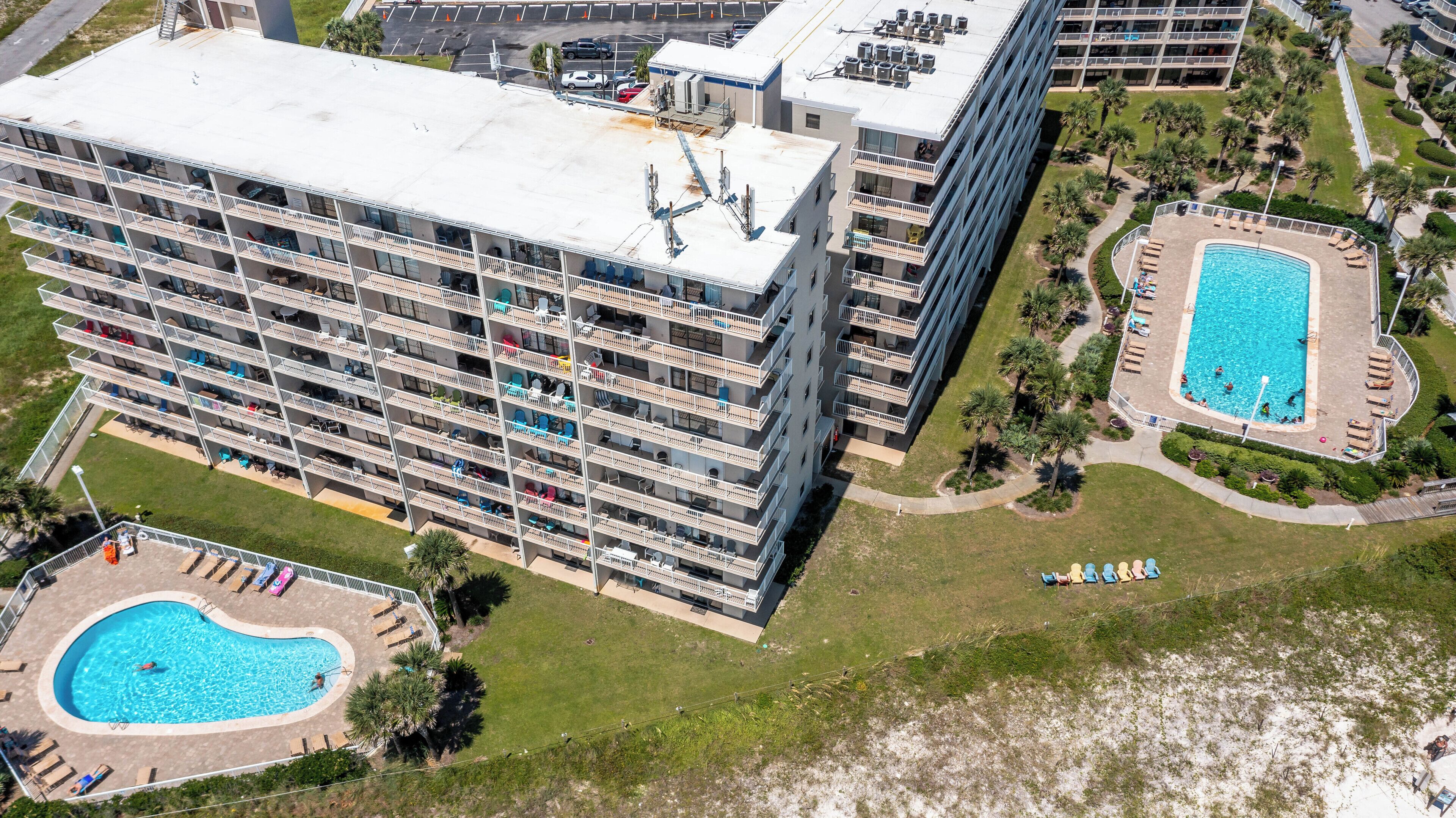 Um hotel moderno com vários sacadões, piscina e área ajardinada.