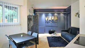 A modern living room with a dining area, a sofa, a coffee table, and a decorative wall with feathers. - Apartment with terrace in residence with swimming pool (Biscarrosse)