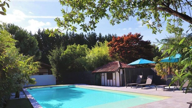 A rectangular swimming pool with a tiled deck surrounding it. There are lounge chairs and a small gazebo with a tiled roof. - Apartment with terrace in residence with swimming pool (Biscarrosse)