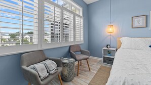 A bedroom with a large window, a bed, a chair, a bedside table, and a lamp. - Spacious condominium close to everything North Myrtle has to offer (North Myrtle Beach)