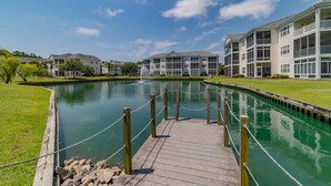 A waterfront property with a dock leading to a pool, surrounded by multi-story buildings with balconies. - Spacious condominium close to everything North Myrtle has to offer (North Myrtle Beach)