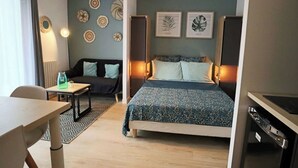 Een moderne hotelkamer met een bed, een bank, een eettafel en een kleine keukenhoek.