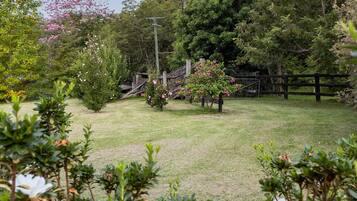 A well-maintained garden with a wooden fence, various shrubs, and flowering plants.
