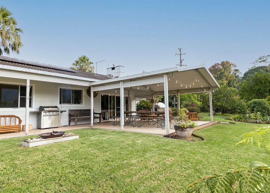 A house with a covered patio, a barbecue, and a lawn.
