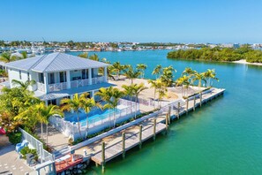 A waterfront property with a dock, a pool, and palm trees.